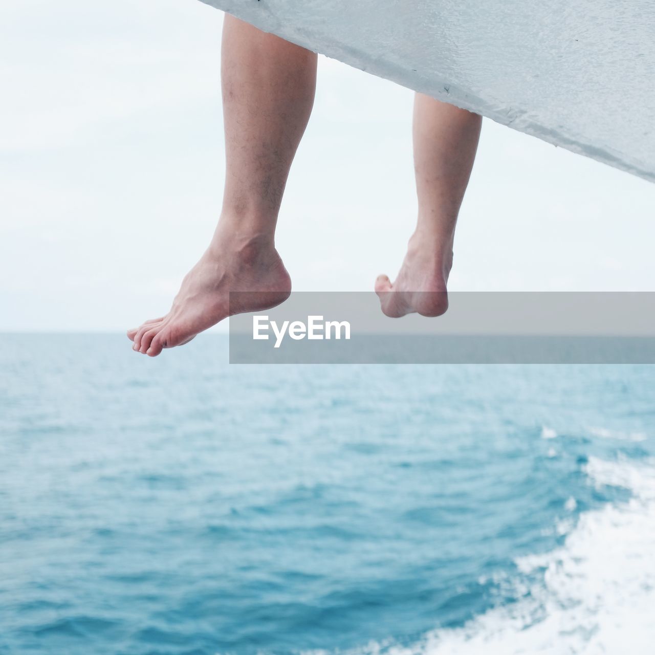 Low section of man sitting over sea