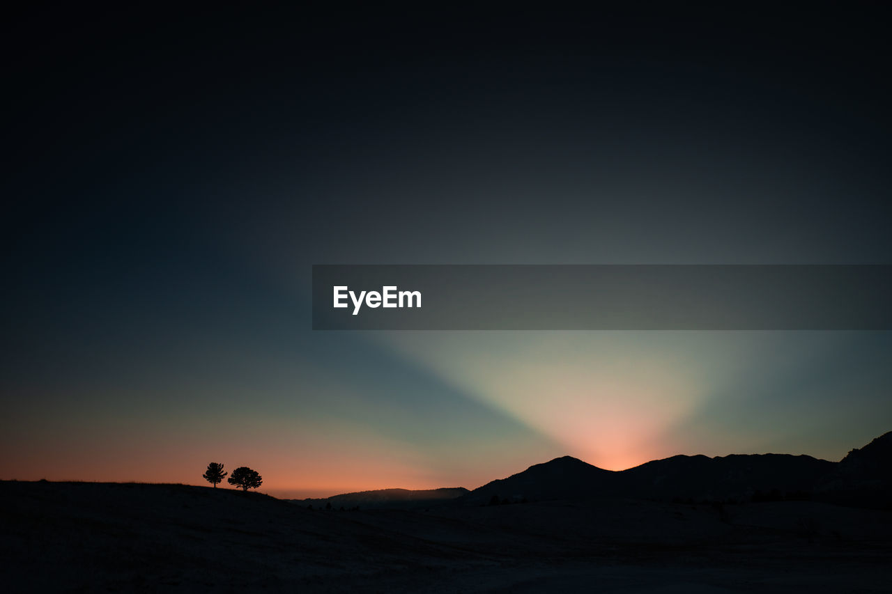 Scenic view of silhouette mountains against clear sky at sunset