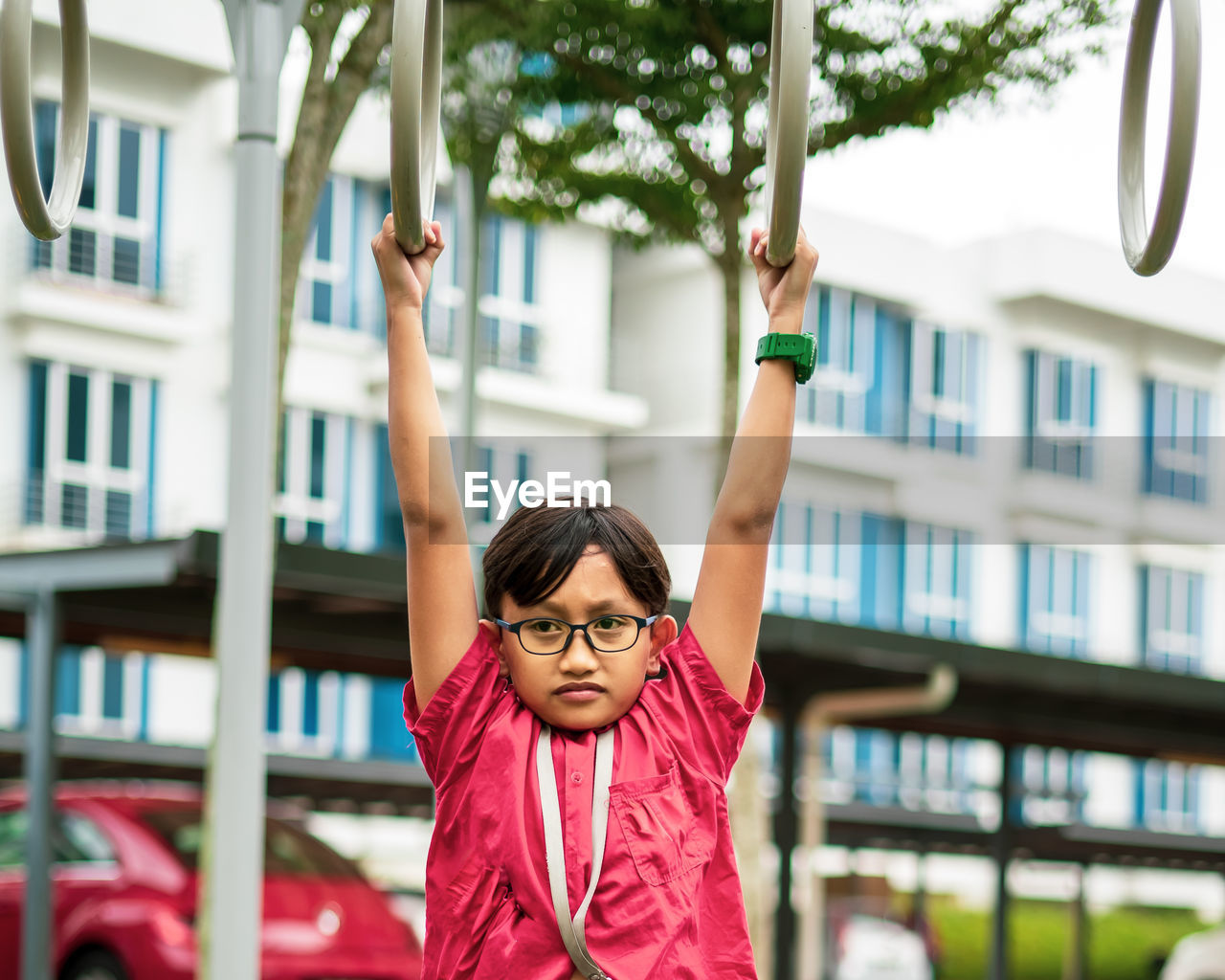 Young asian children hang on the monkey bar. to exercise at outdoor playground in the neighbourhood.