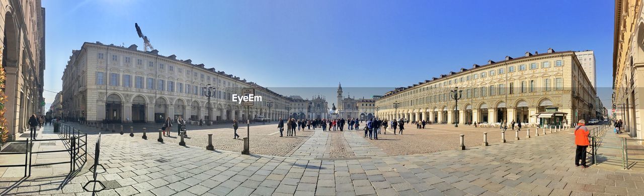 Panoramic view of people at town square against clear sky
