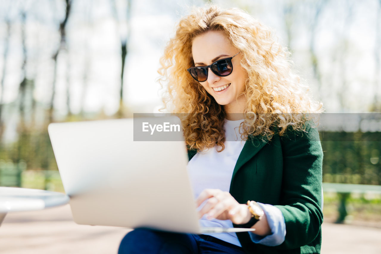 YOUNG WOMAN USING MOBILE PHONE IN LAPTOP ON SMART