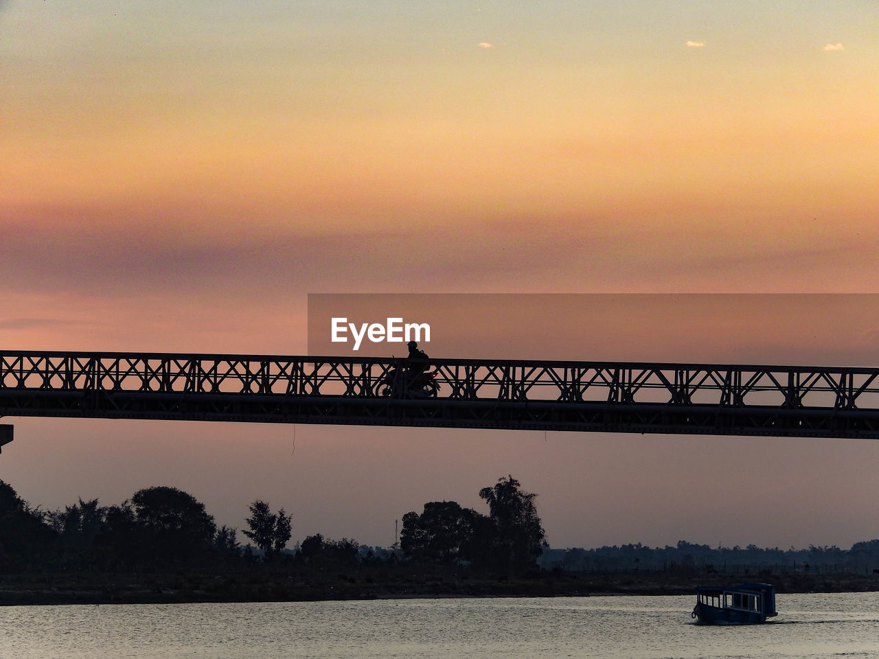 Silhouette bridge over sea against sky during sunset