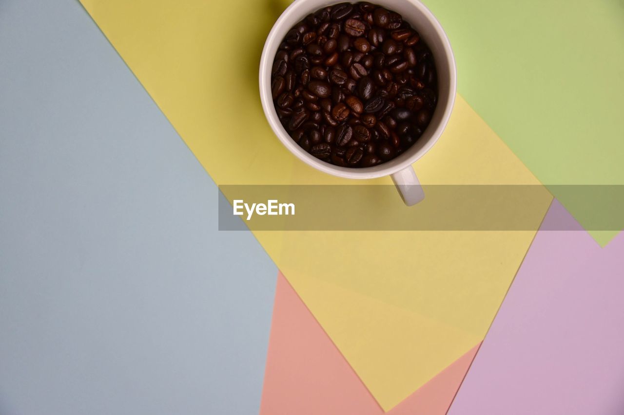 HIGH ANGLE VIEW OF COFFEE CUP ON TABLE AGAINST WALL