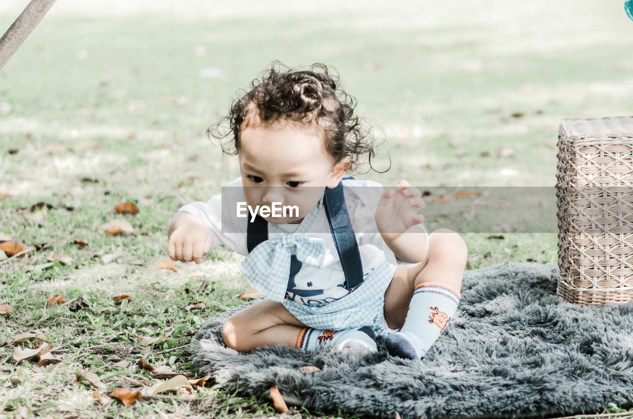 Cute baby girl sitting on grass outdoors