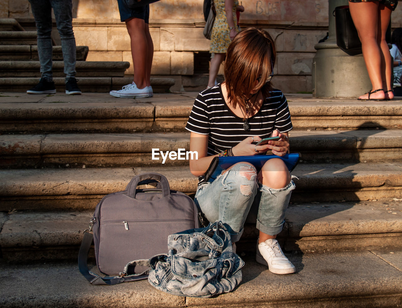 Full length of teenage girl using mobile phone while sitting on steps