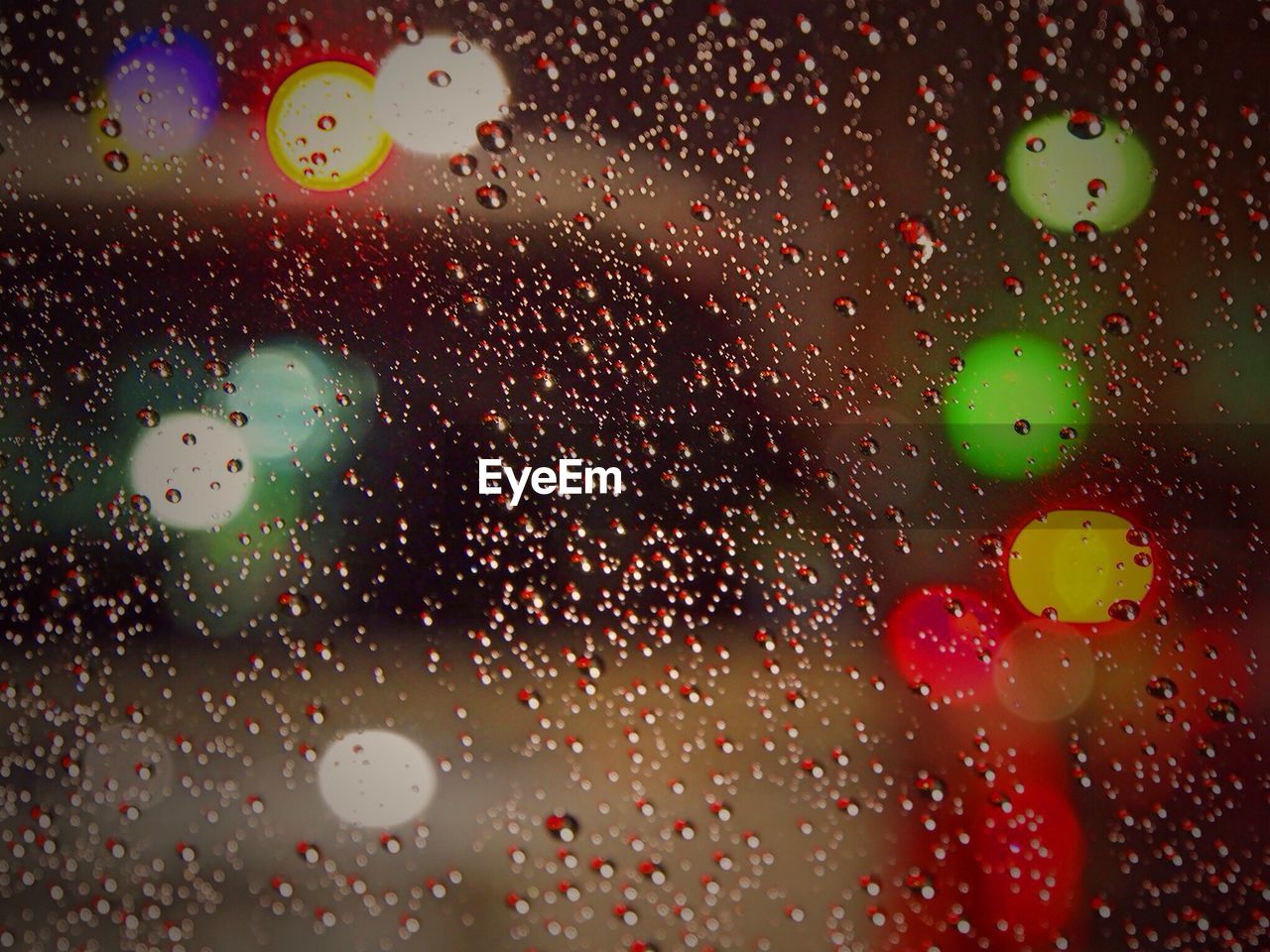 FULL FRAME SHOT OF RAINDROPS ON ILLUMINATED GLASS