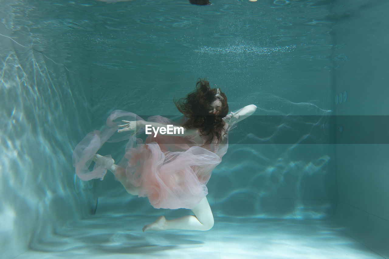 YOUNG WOMAN SWIMMING IN POOL