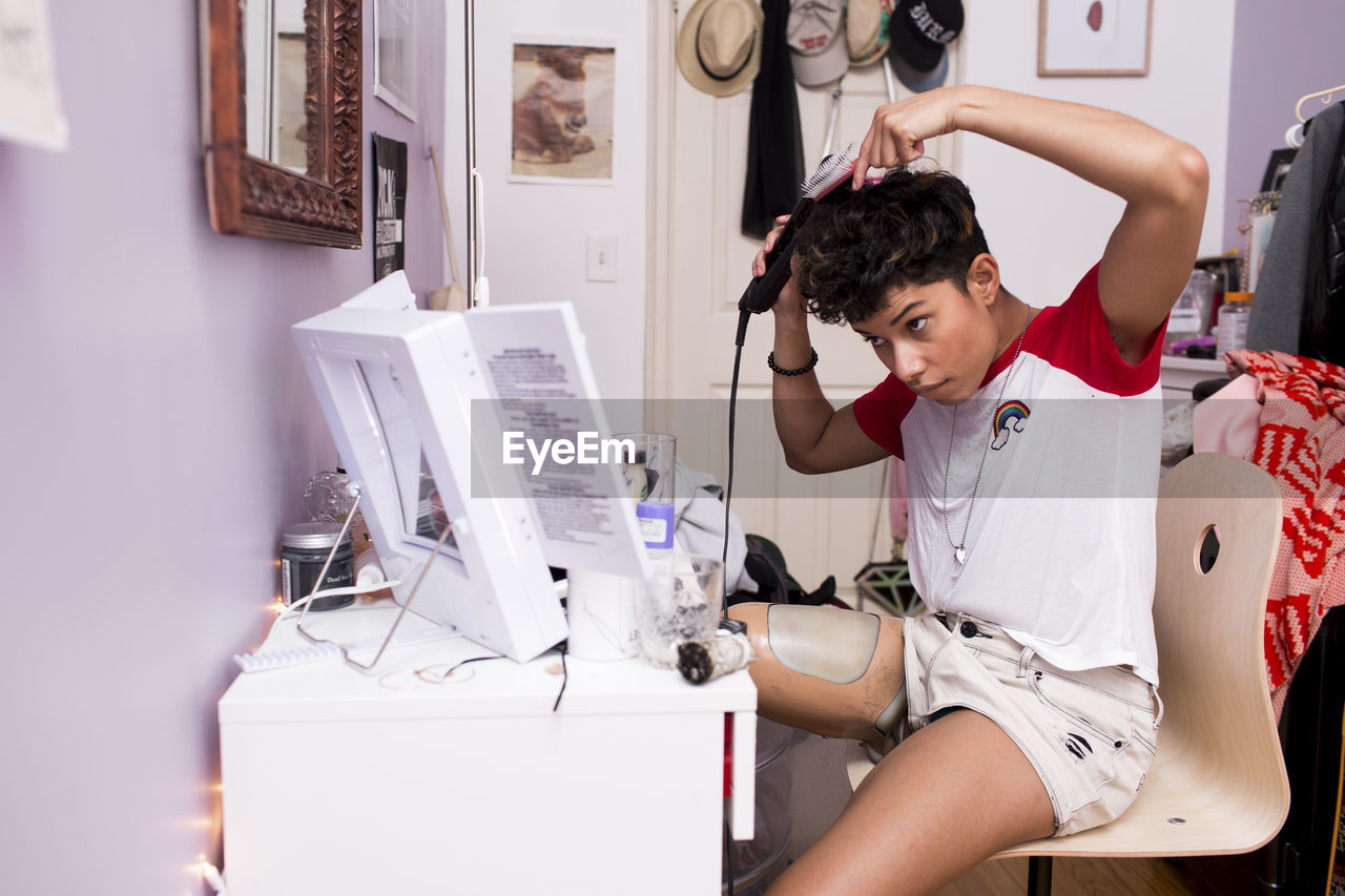 Disabled woman using straightening machine while looking in mirror