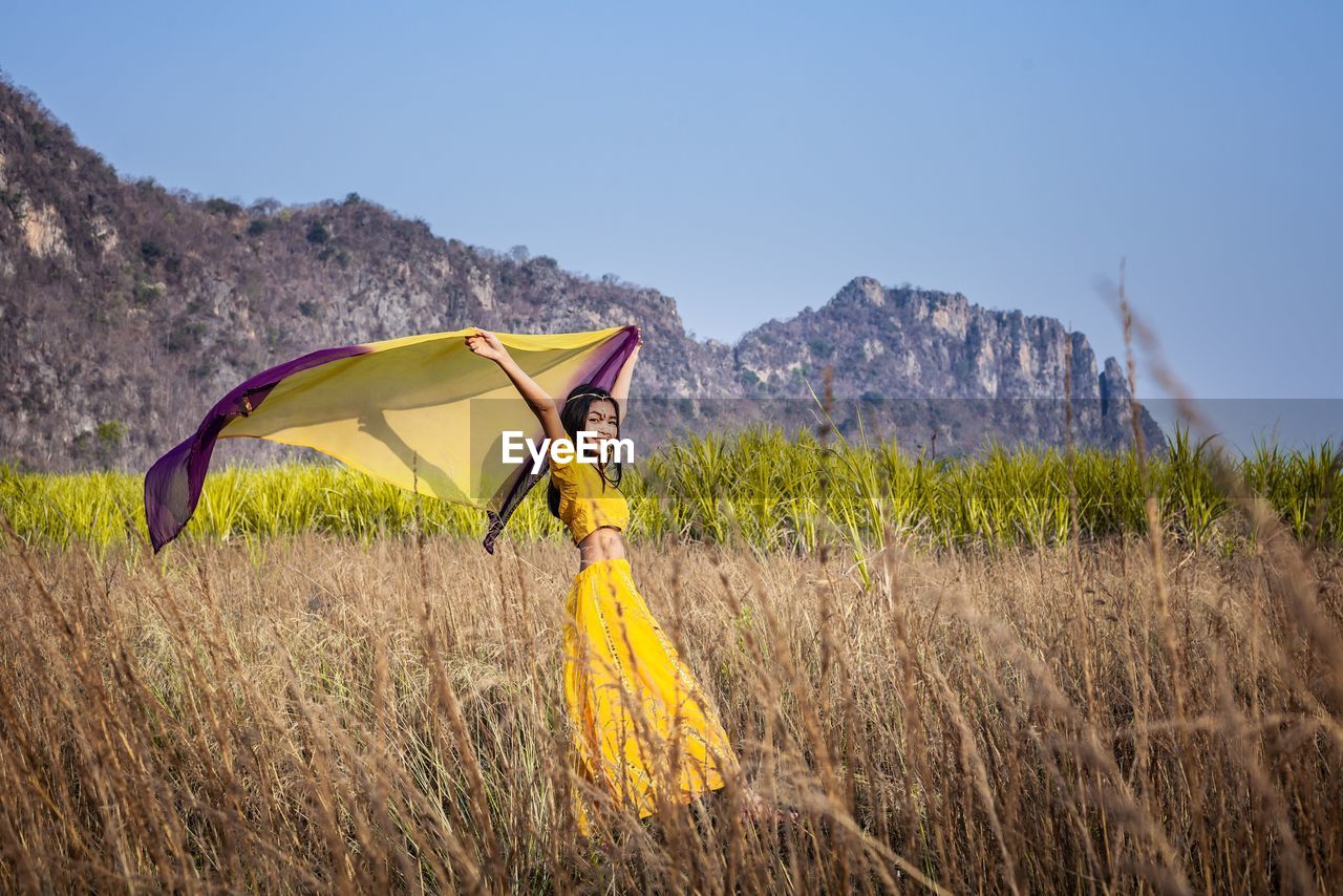 A beautiful woman in an indian dress stands fluttering in the valley and the wind.