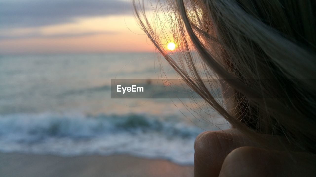 Close-up of woman against sea at sunset