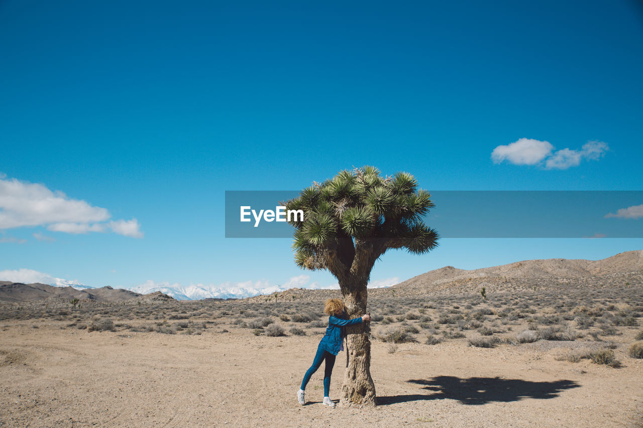 Full length of woman hugging tree at death valley national park against sky