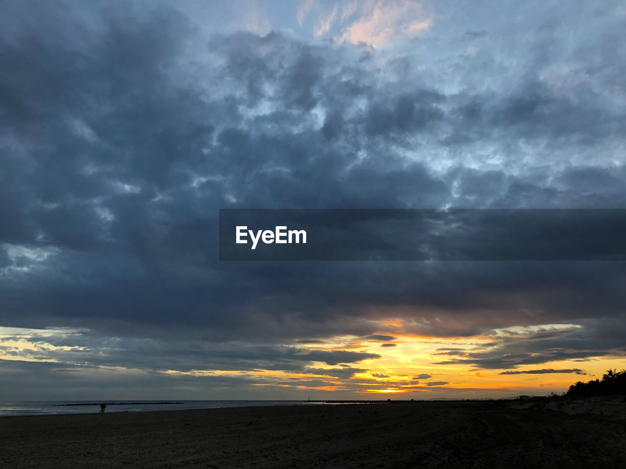 STORM CLOUDS OVER LAND DURING SUNSET