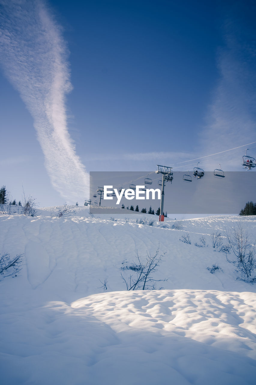Scenic view of snow covered field against sky and ski lift