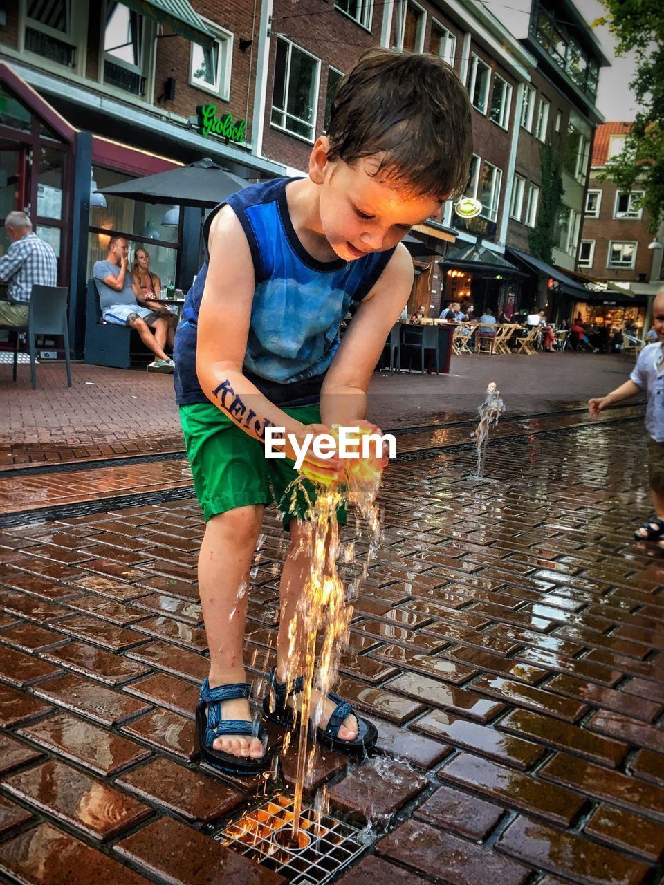 Boy playing with illuminated fountain at town square