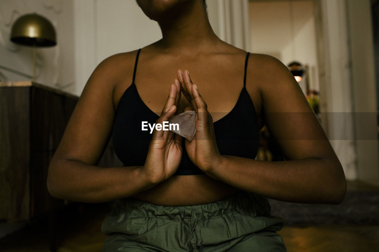 Midsection of woman holding crystal while exercising at home