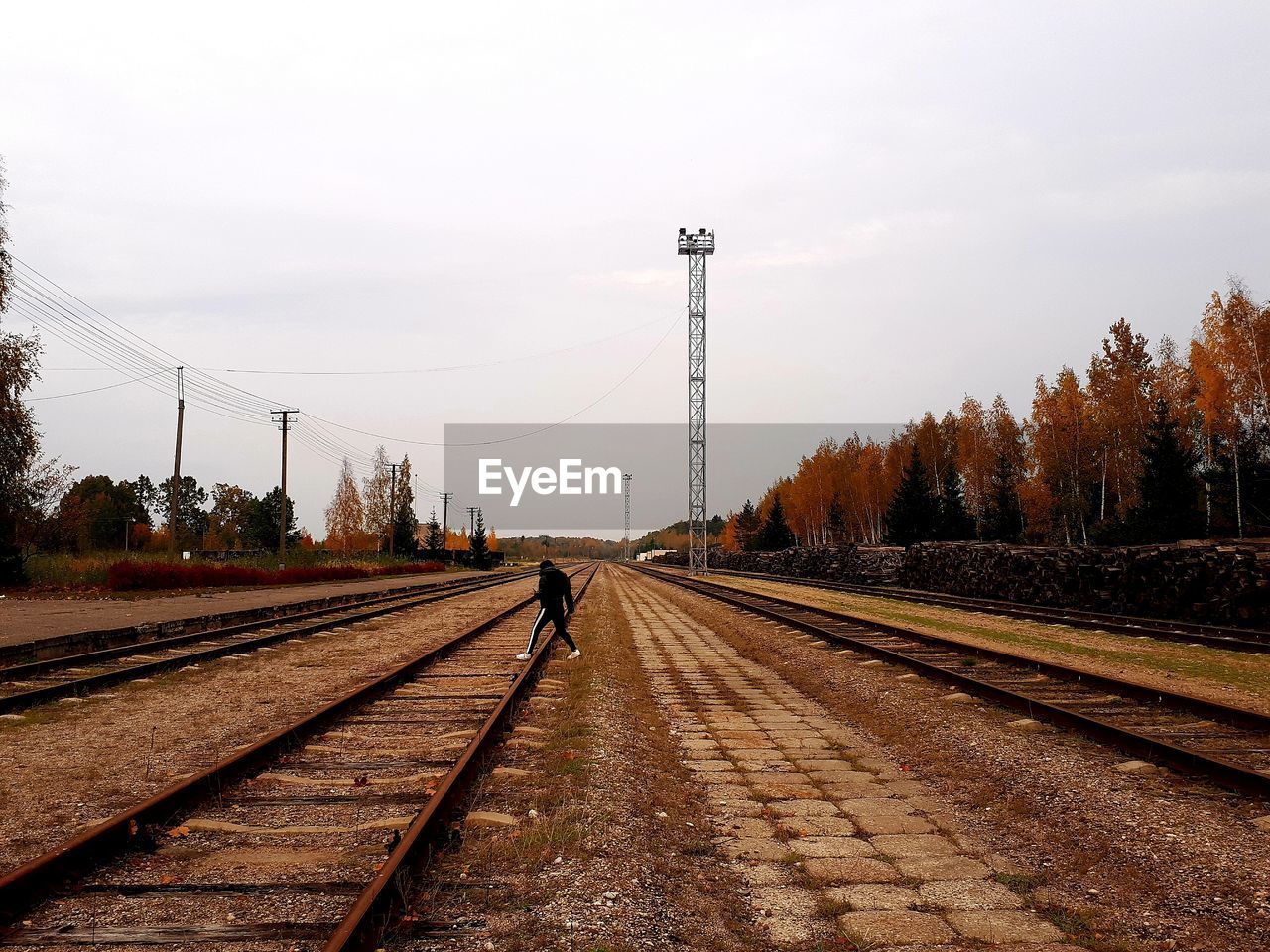 REAR VIEW OF MAN WALKING ON RAILROAD TRACK