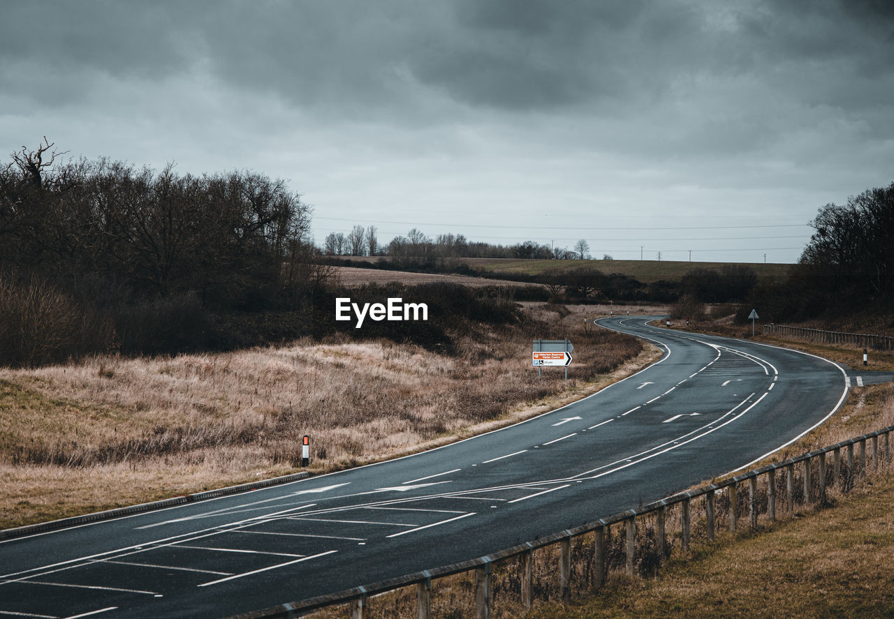 Empty road amidst trees against sky