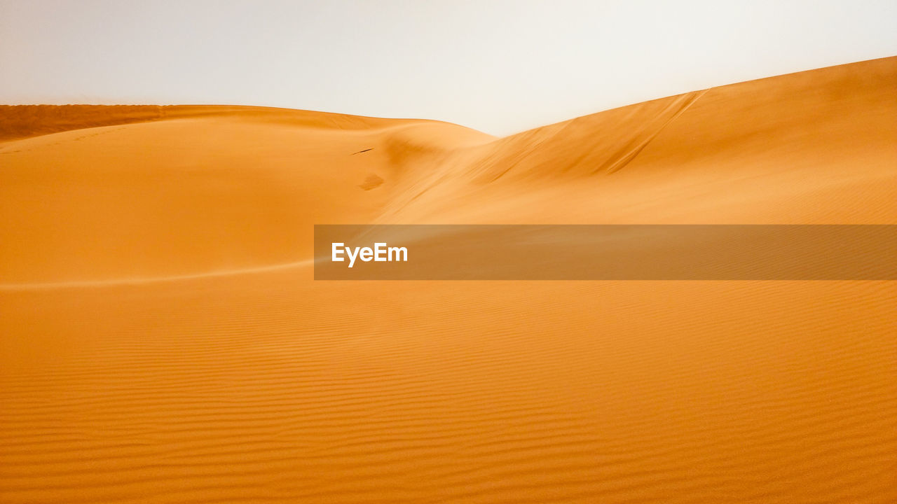 Sand dunes in desert against sky