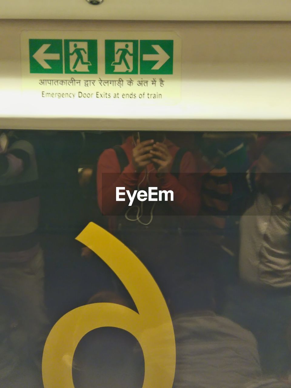 Reflection of person photographing emergency exit sign in train