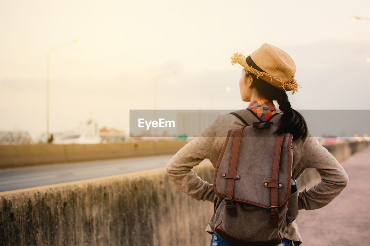 Rear view of woman standing on bridge against sky