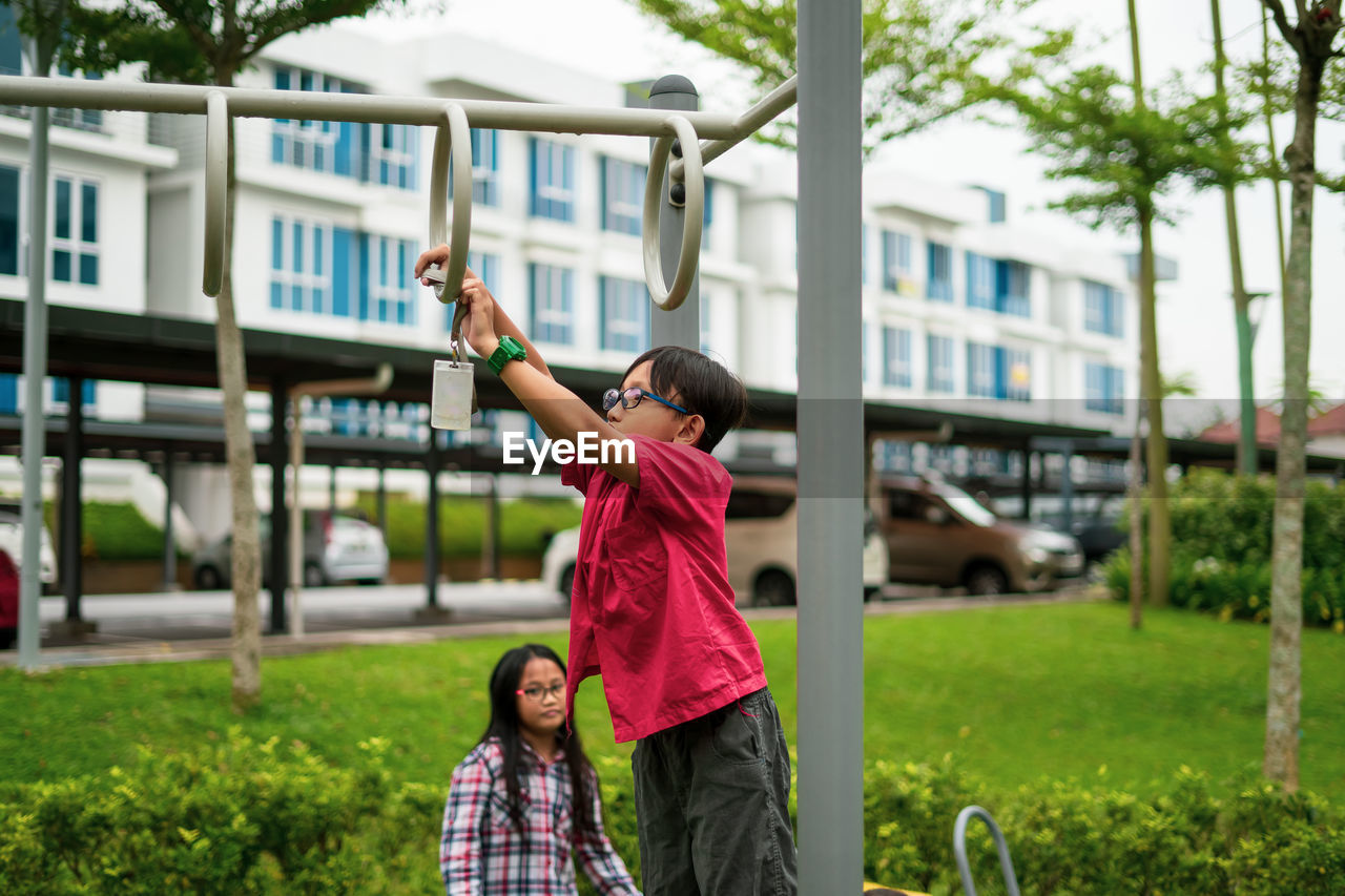 Young asian children hang on the monkey bar. to exercise at outdoor playground in the neighbourhood.