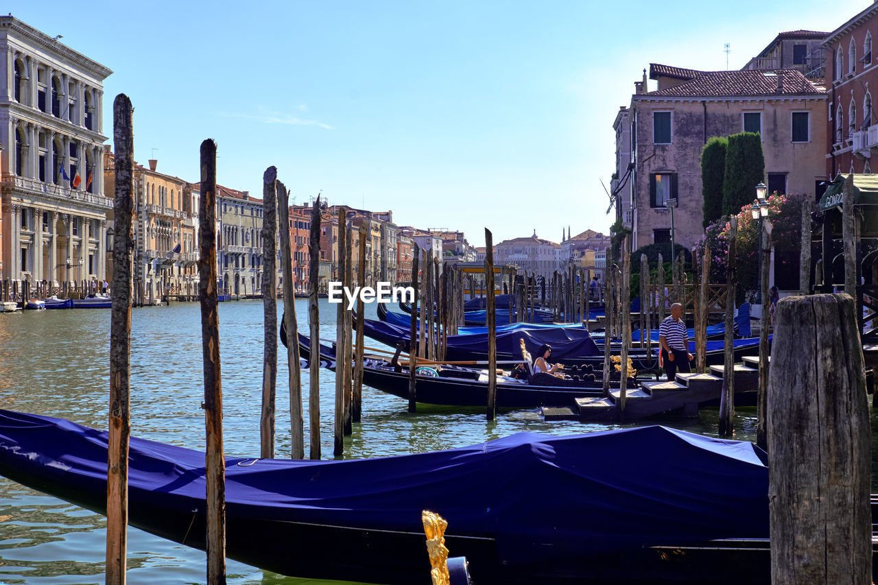 Gondolas moored in canal against buildings