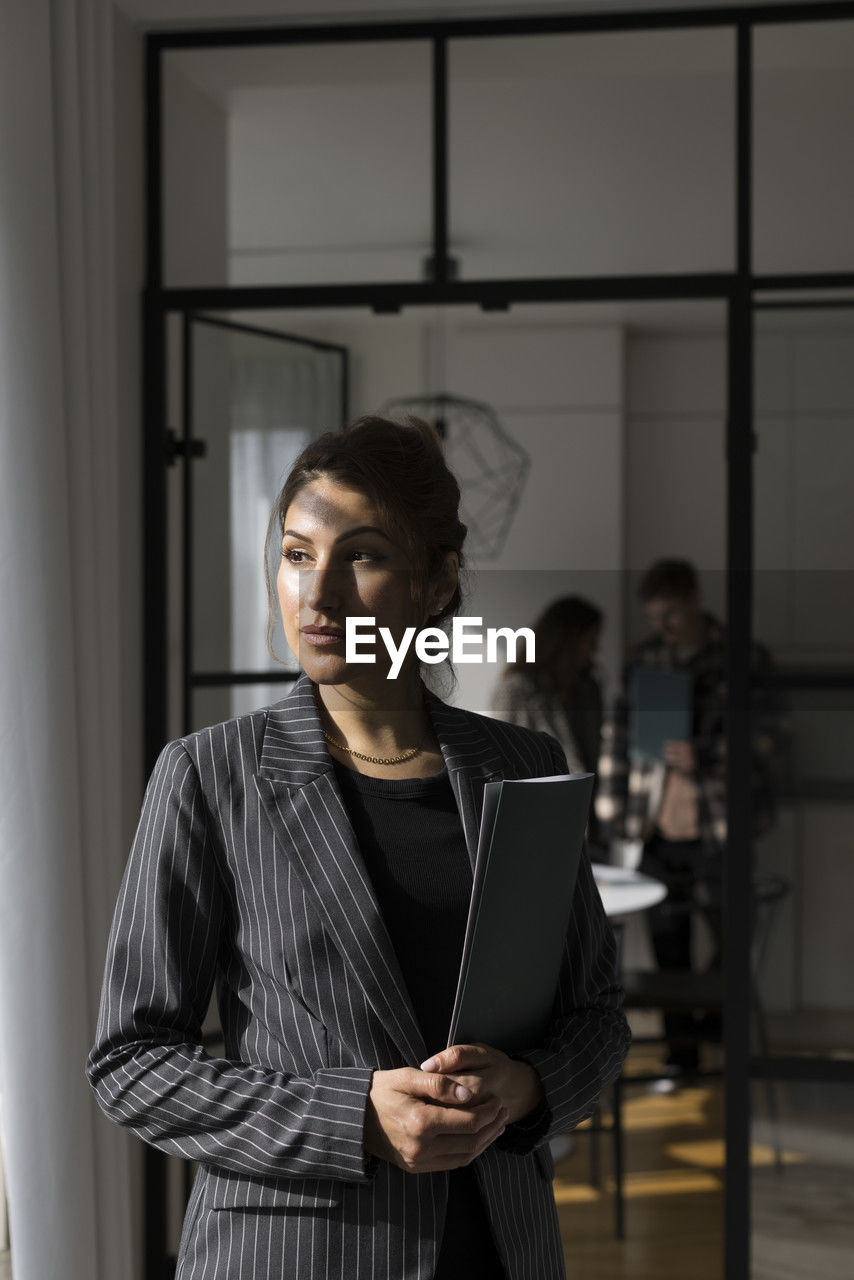 Saleswoman looking away while holding folder at new home