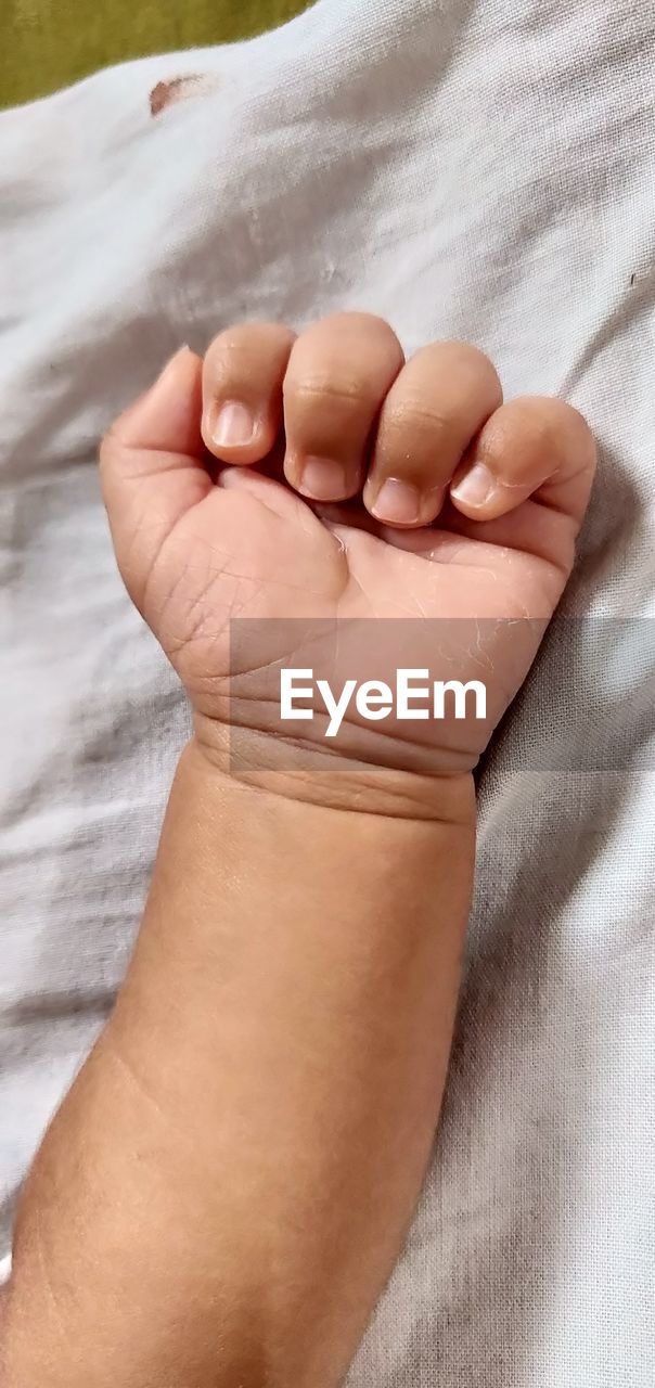 Close-up of human hand on bed