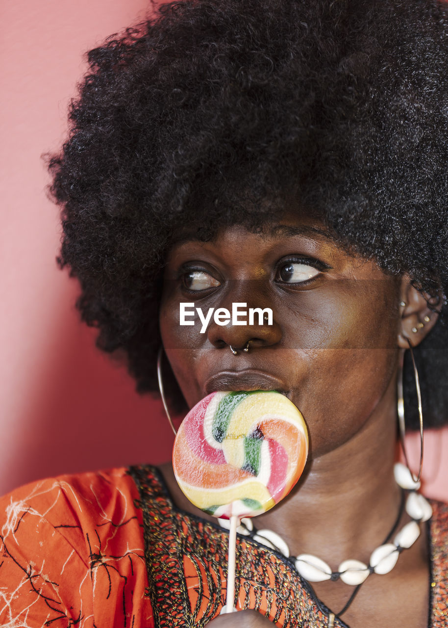 African woman wearing african hair eating on a candy stick