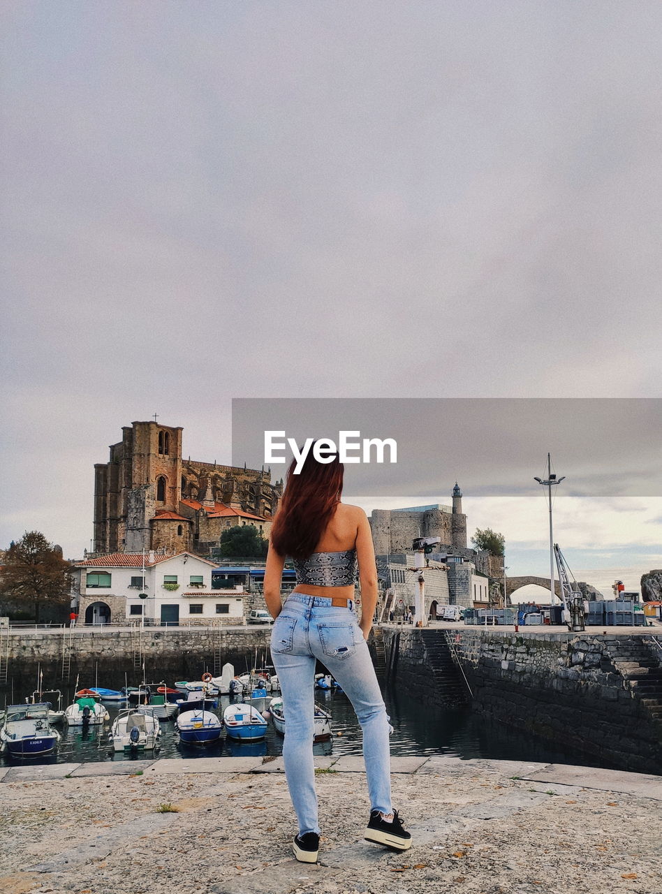 Rear view of woman standing by cityscape against sky