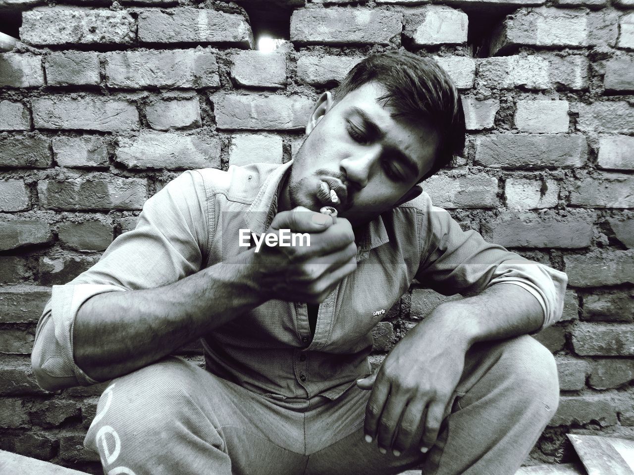 Young man smoking cigarette while sitting outdoors