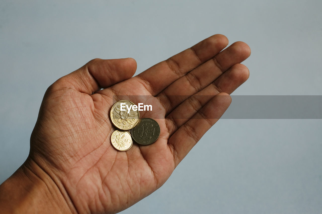 hand, finance, coin, currency, one person, business, holding, wealth, close-up, studio shot, savings, finance and economy, money, indoors, adult, investment, gold, business finance and industry, gray background, finger, cash, economy