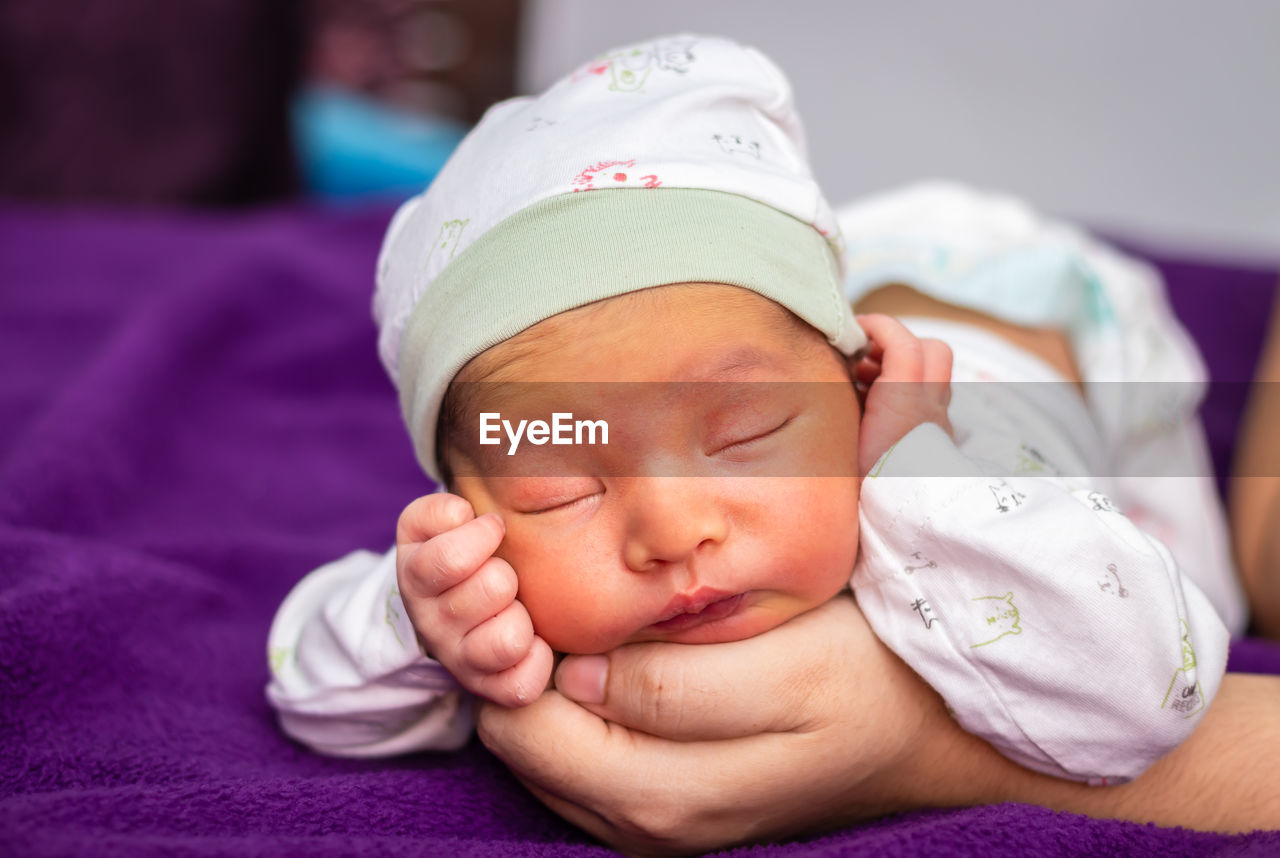 Close-up of cute baby boy sleeping on bed at home