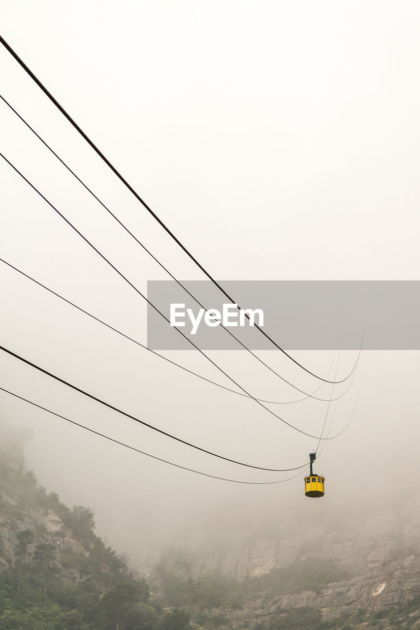 Overhead cable car against sky during foggy weather