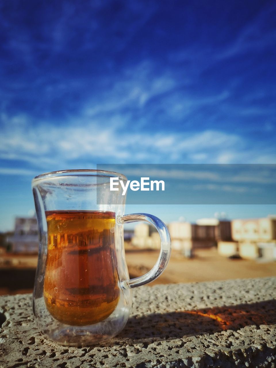 CLOSE-UP OF BEER GLASS ON SAND