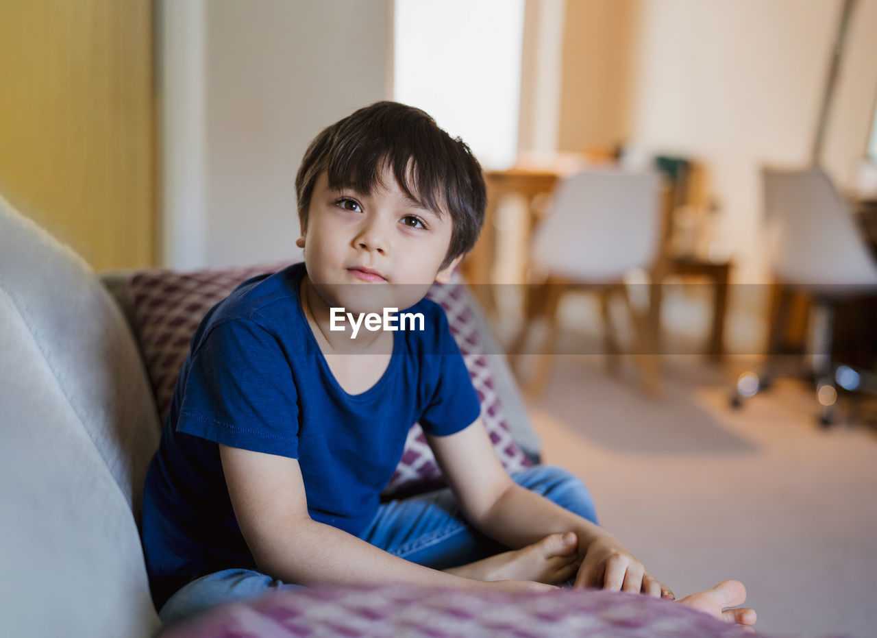 Portrait of boy sitting on sofa at home