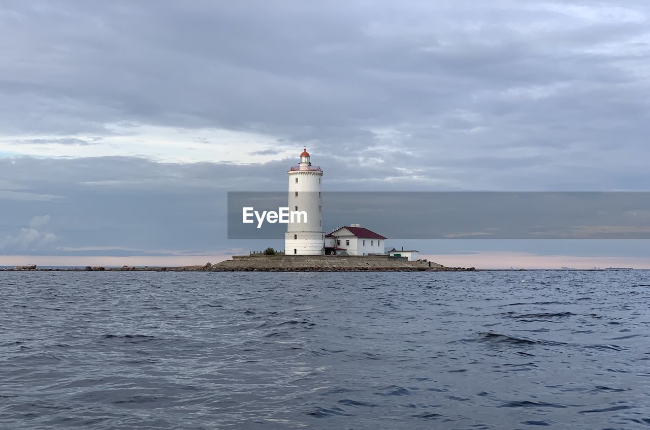 Lighthouse by sea against sky