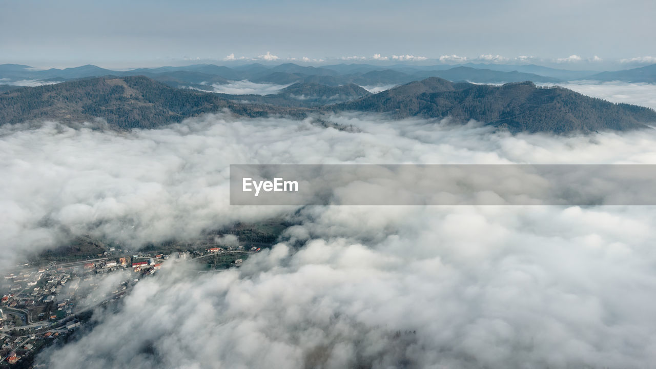Above the clouds. foggy layered mountain landscape with a city in carpathians, ukraine.