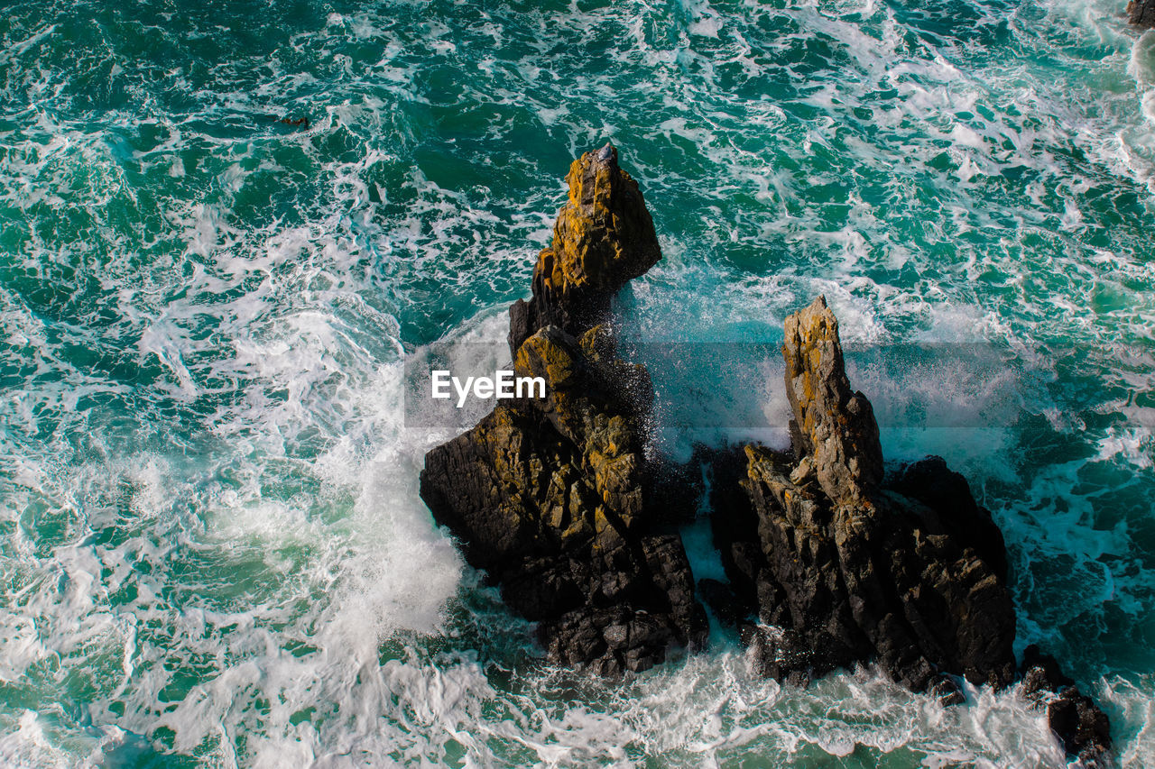 HIGH ANGLE VIEW OF ROCKS AT SEA SHORE