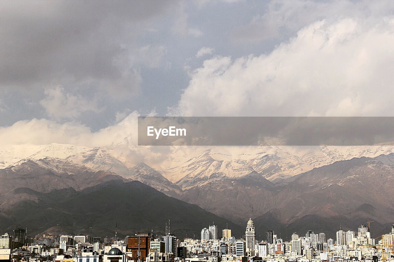 City by snow covered mountains against sky