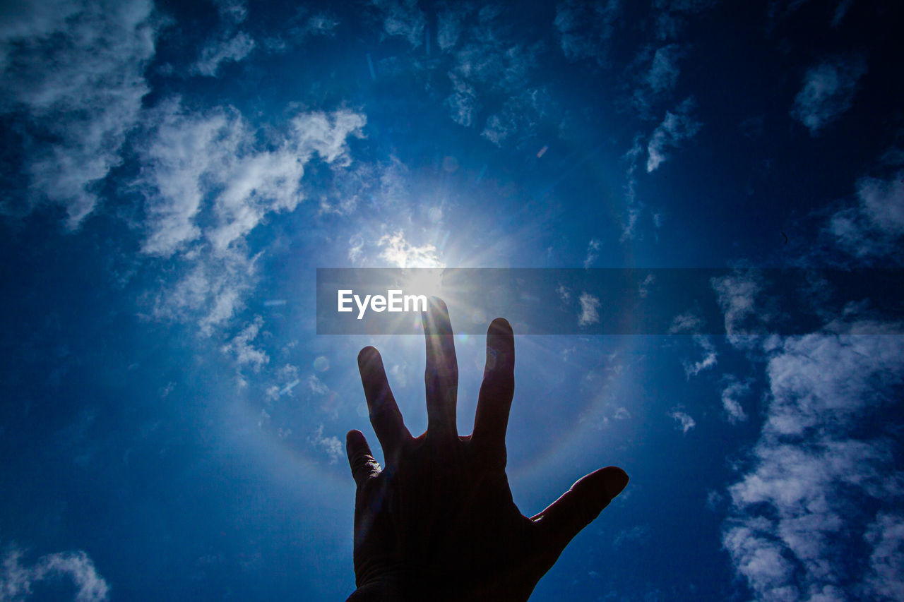 sky, hand, blue, nature, one person, cloud, sunlight, light, silhouette, low angle view, darkness, back lit, sunbeam, finger, outdoors, hope