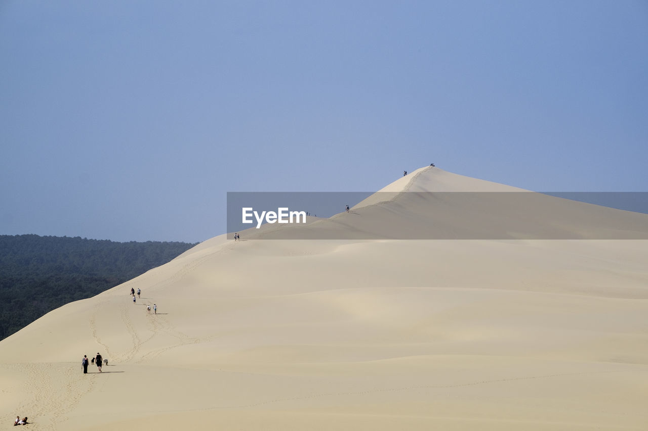 Rear view of people at dune of pilat against clear sky