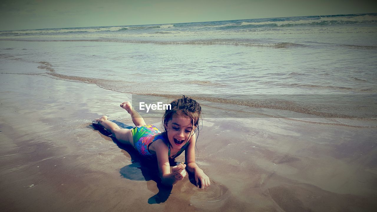 Full length of girl lying down on shore at beach