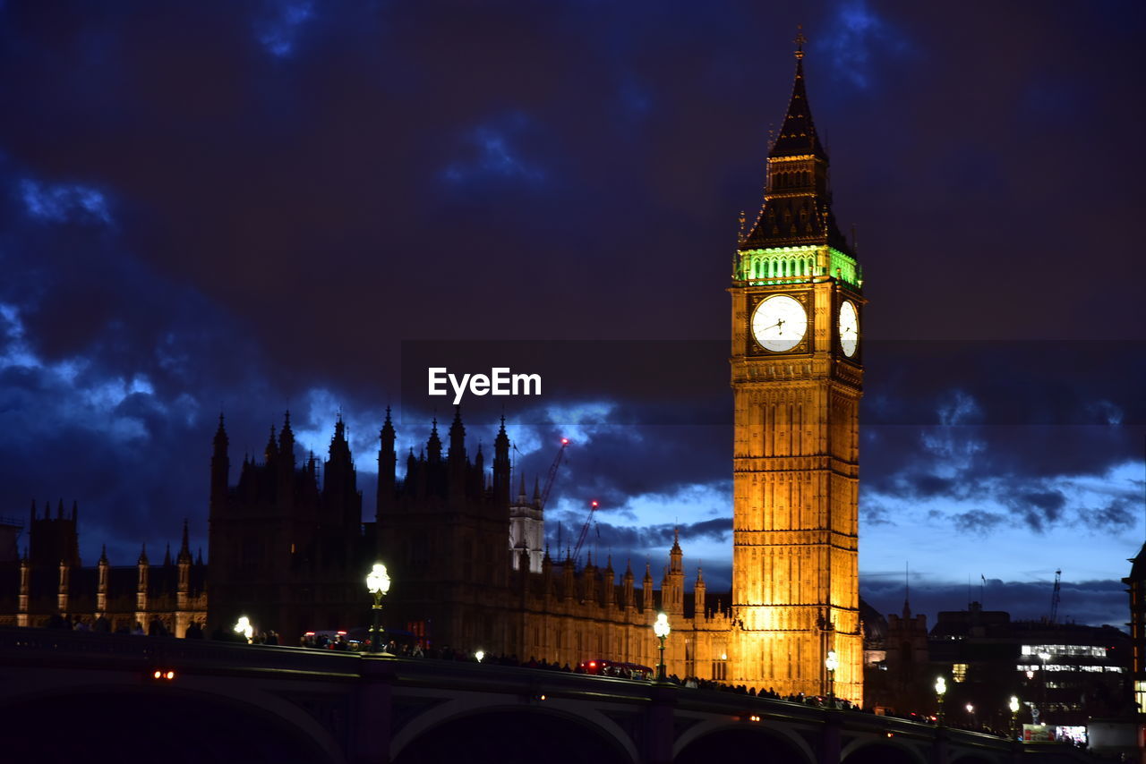 Illuminated tower amidst buildings in city at night