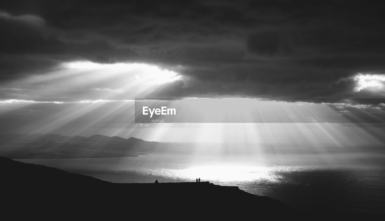 Scenic view of sea against cloudy sky on sunny day