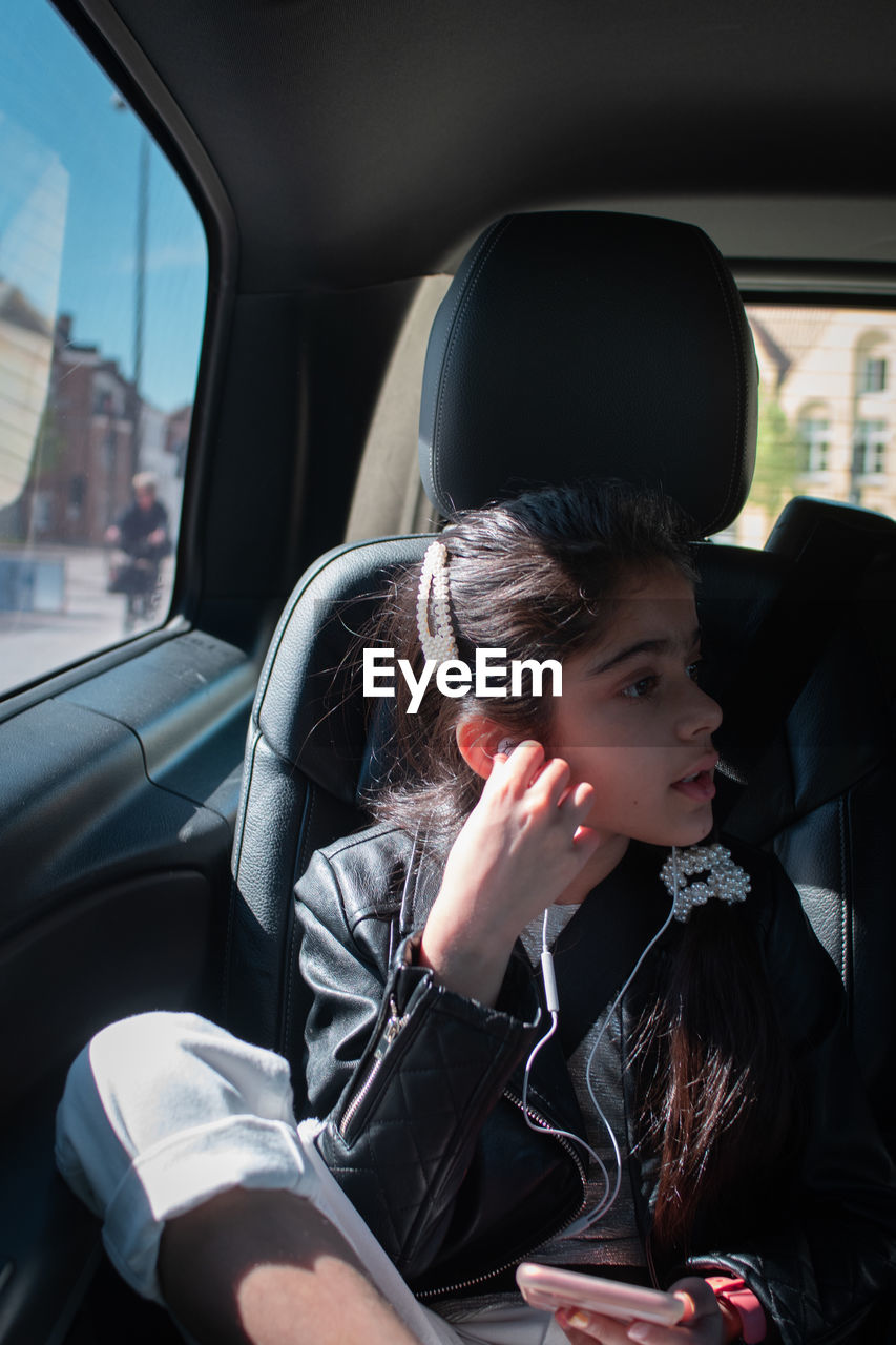 Young girl using mobile phone while sitting in car