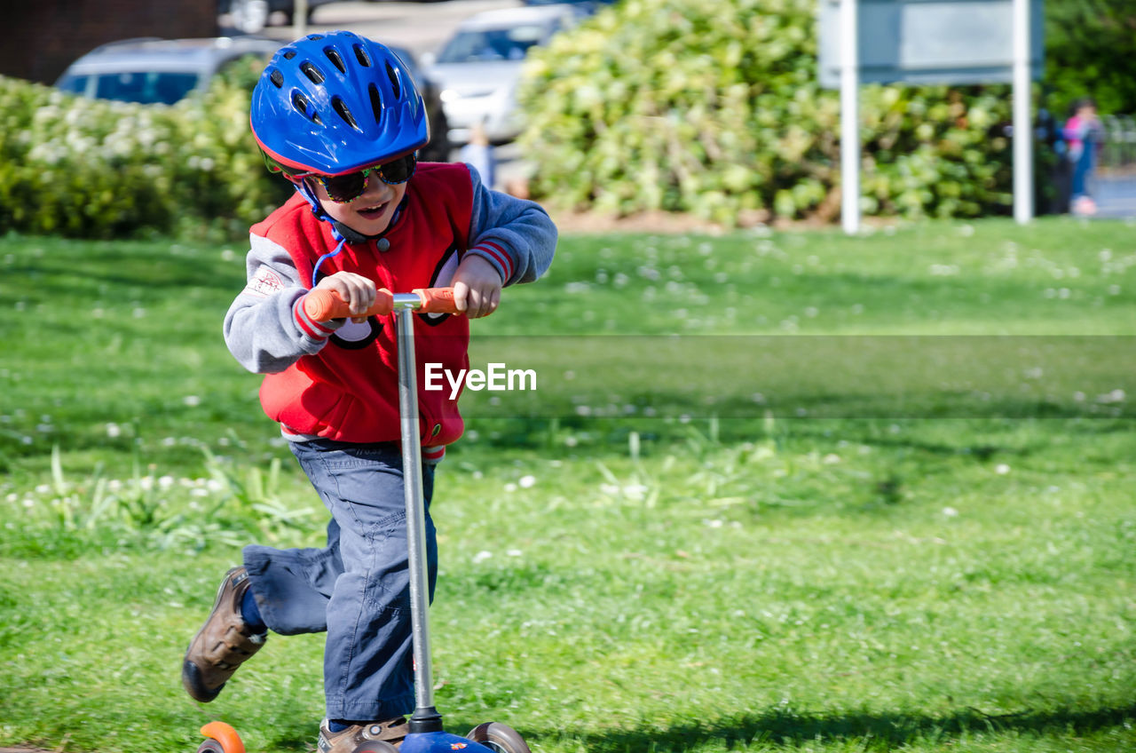 Cute boy riding push scooter at park