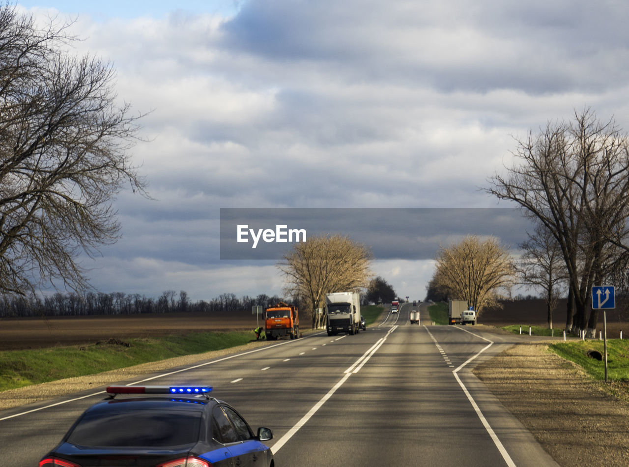 Cars on road against cloudy sky