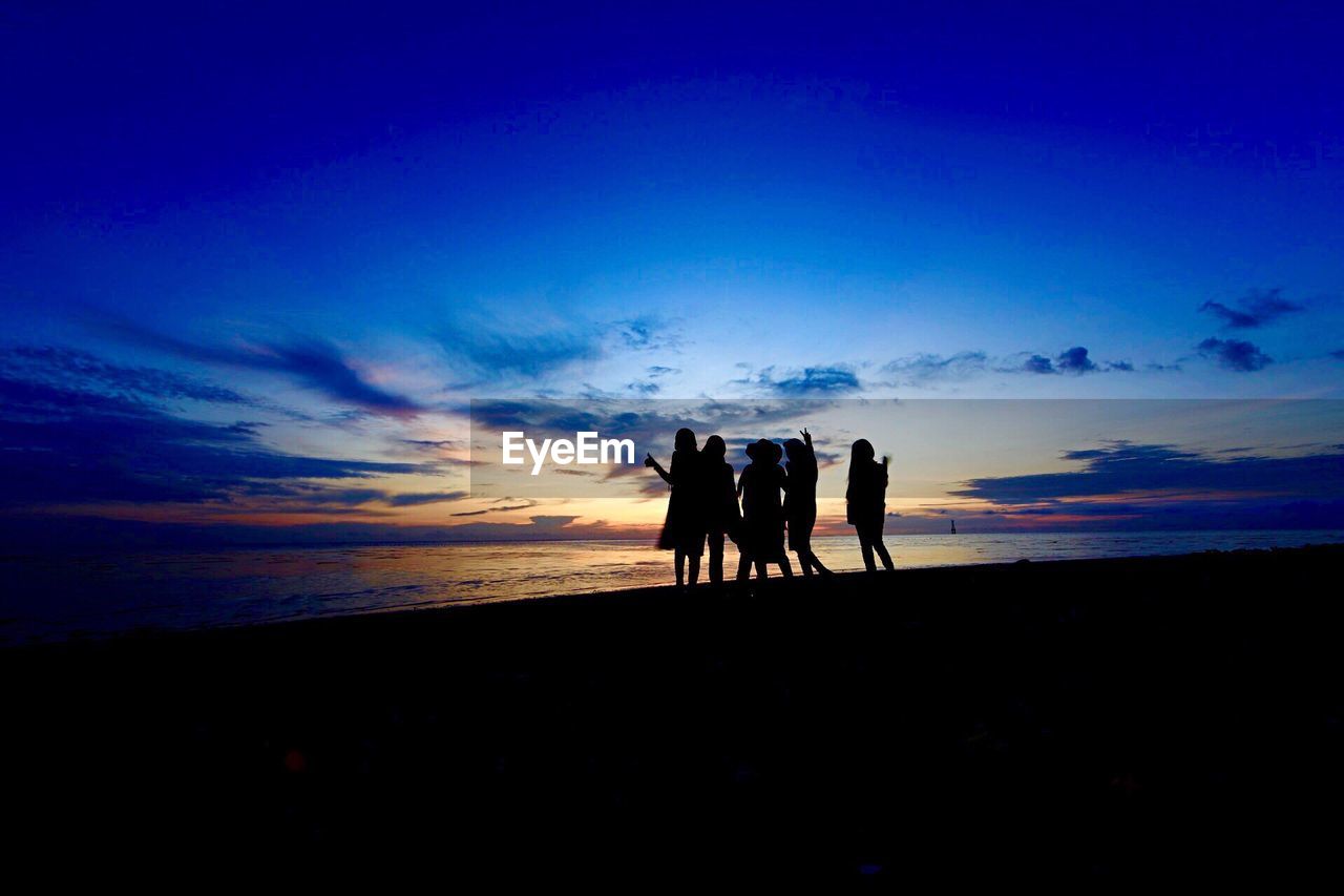 Silhouette of friends enjoying on beach