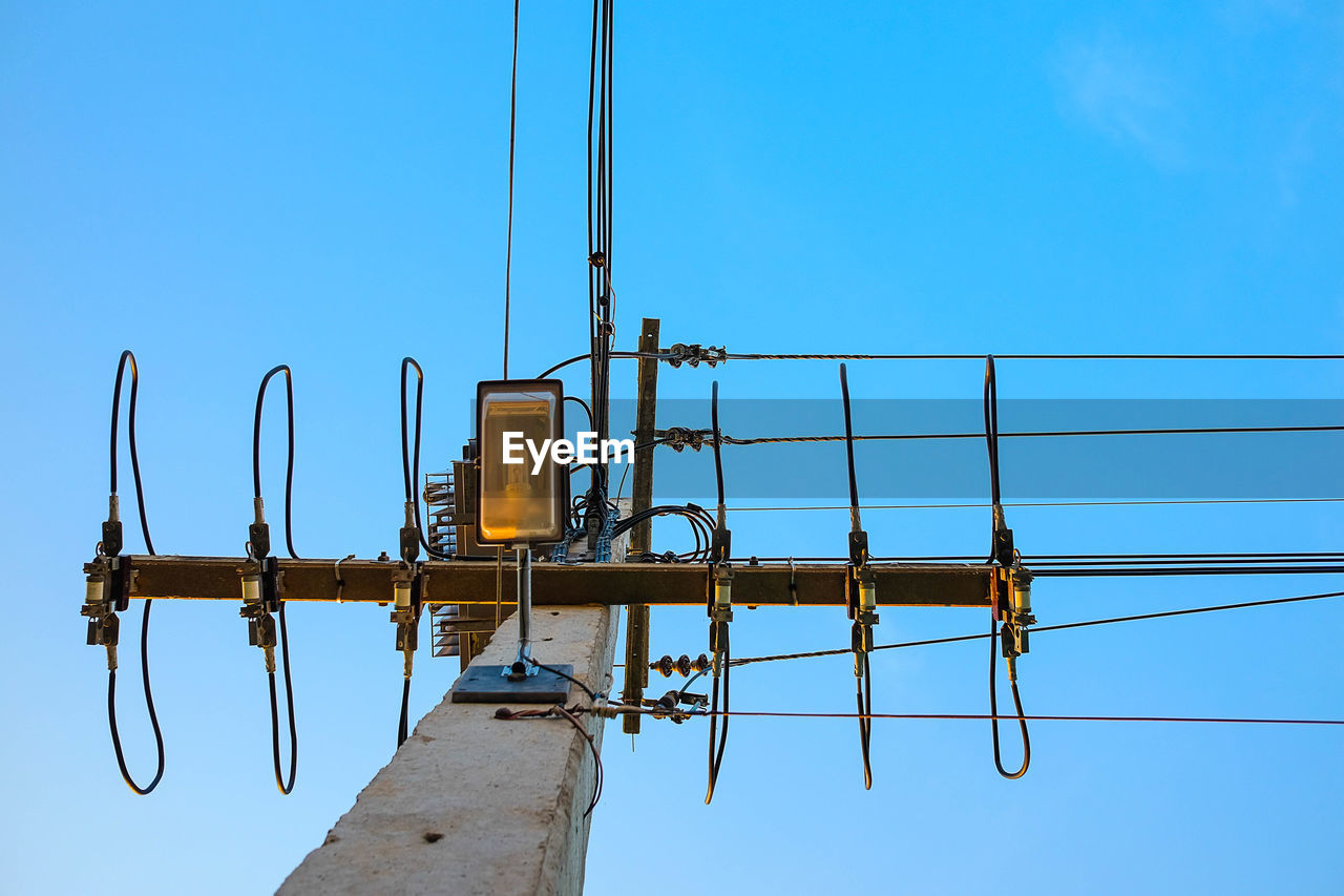 Low angle view of telephone pole against clear blue sky